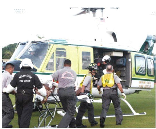 A helicopter with people in it and some of them are holding on to the door.