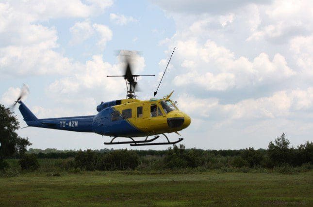 A helicopter flying over the grass in the sky.