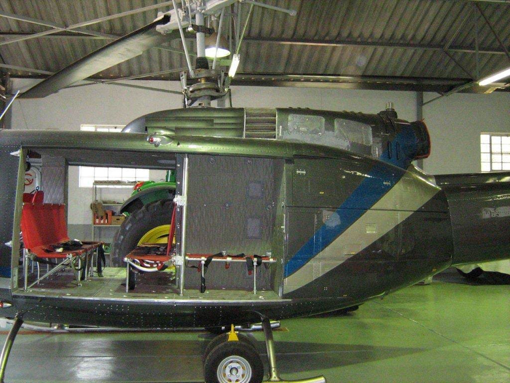 A helicopter in an airplane hanger with its door open.