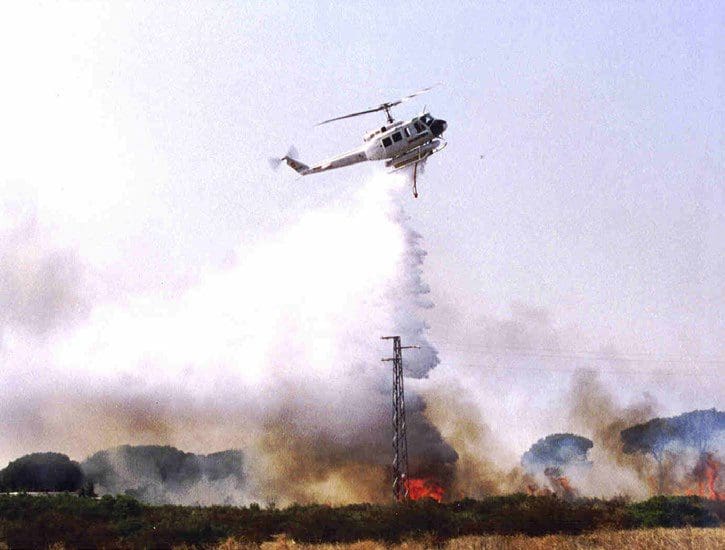 A helicopter is flying over the fire.