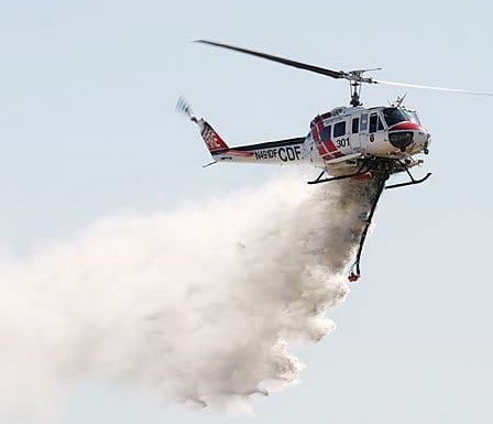 A helicopter releasing water on the ground.