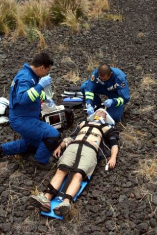 Two men in blue suits and one man is lying on a ground