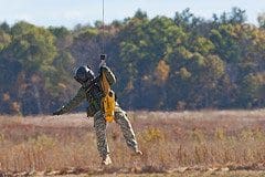 A soldier is hanging from the side of a wire.