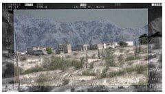 A view of some buildings and mountains from the desert.